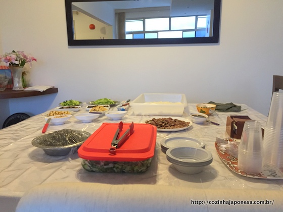 Mesa com arroz de sushi e ingredientes do recheio para o temaki. Sunomono no vasilhame grande.