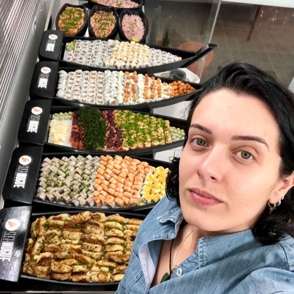 Tamires junto a algumas barcas de sushi prontas para delivery (Sushi Nogue)